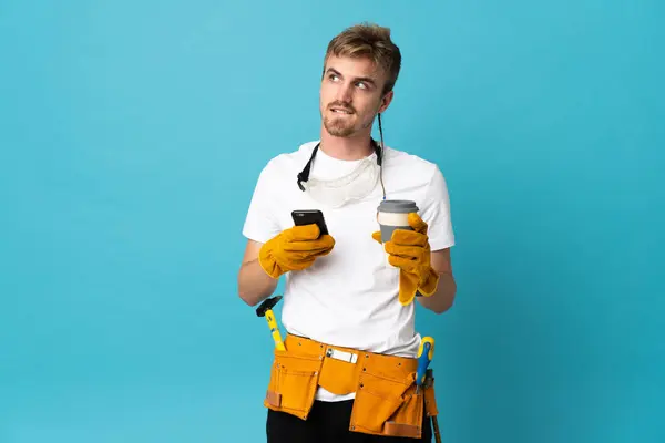 Jovem Eletricista Homem Sobre Parede Isolada Segurando Café Para Tirar — Fotografia de Stock