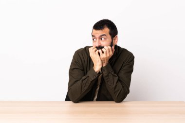 Masada sakallı beyaz bir adam gergin ve korkmuş bir şekilde elleriyle suni teneffüs yapıyor..