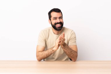 Masada sakallı beyaz bir adam bir konferanstan sonra alkışlıyor..