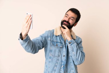 İzole edilmiş arka planda sakallı beyaz bir adam selfie çekiyor.