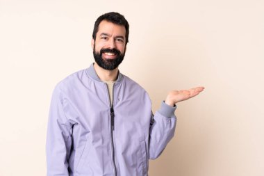 Sakallı beyaz bir adam, izole edilmiş arka planda ceket giyiyor. Bir ilan vermek için avuç içinde hayali bir fotokopi makinesi tutuyor.