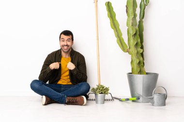 Bahçıvan yerde oturuyor. Kapalı bir yerde. Yüzünde sürpriz bir ifade var.