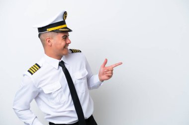 Uçak pilotu beyaz arka planda izole edilmiş beyaz bir beyaz adam parmak göstererek bir ürün sunuyor.