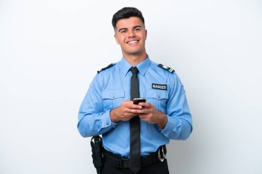 Young police caucasian man isolated on white background sending a message with the mobile