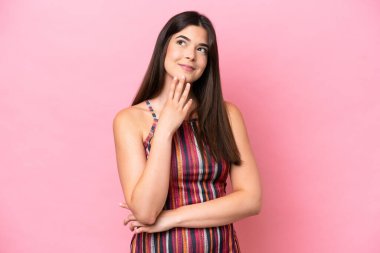 Young Brazilian woman isolated on pink background looking up while smiling