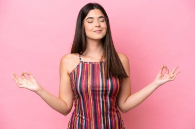 Zen pozisyonunda pembe arka planda izole edilmiş genç Brezilyalı kadın.