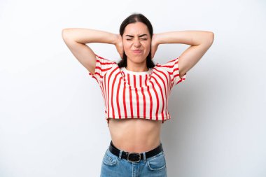 Beyaz arka planda izole edilmiş genç beyaz kadın hayal kırıklığına uğramış ve kulaklarını kapatmış.