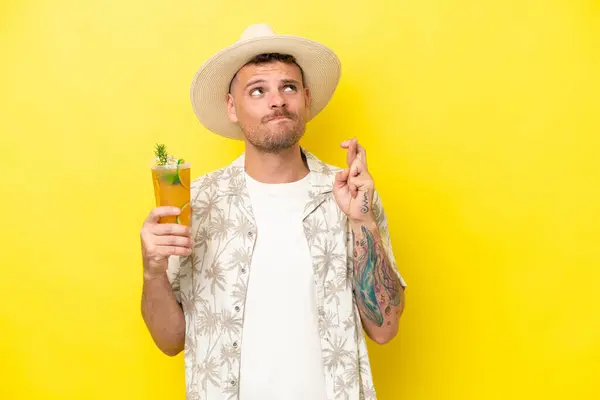 Young Caucasian Man Holding Cocktail Isolated Yellow Background Fingers Crossing — Stock Photo, Image