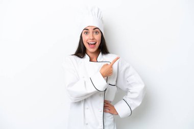 Beyaz arka plandaki genç aşçı kadın şaşırmış ve işaret ediyor.