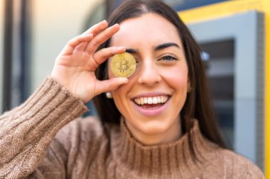 Dışarıda Bitcoin tutan genç bir kadın.