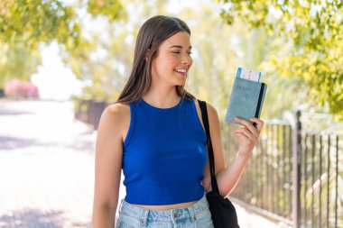 Genç ve güzel Brezilyalı bir kadın elinde pasaport ile dışarıda mutlu bir ifadeyle bekliyor.