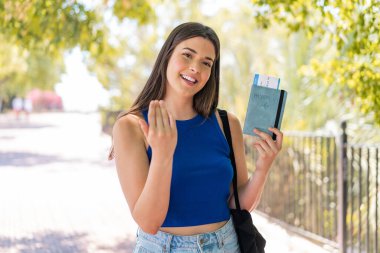 Dışarıda pasaport tutan genç, güzel Brezilyalı bir kadın. Eli ile gelmesi için davet ediyor. Gelmene sevindim.