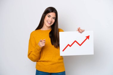 Beyaz arka planda izole edilmiş genç Brezilyalı bir kadın elinde büyüyen bir istatistik oku sembolü olan bir tabela tutuyor ve ön tarafı işaret ediyor.