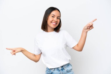 Beyaz arka planda izole edilmiş genç beyaz kadın parmak uçlarını işaret ediyor ve mutlu.