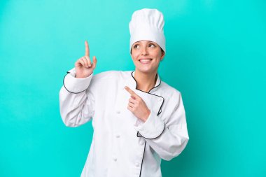 Kafkasyalı genç aşçı kadın mavi arka planda izole edilmiş işaret parmağıyla işaret etmek harika bir fikir.