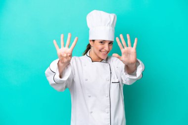 Kafkasyalı genç aşçı kadın mavi arka planda izole edilmiş dokuz parmaklı sayıyor.