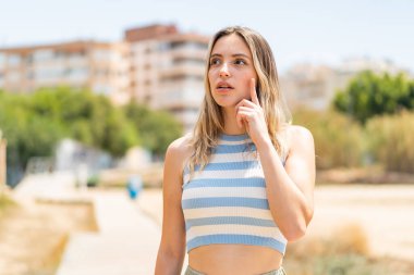 Açık havada genç ve güzel bir kadın parmak kaldırmayı düşünüyor.