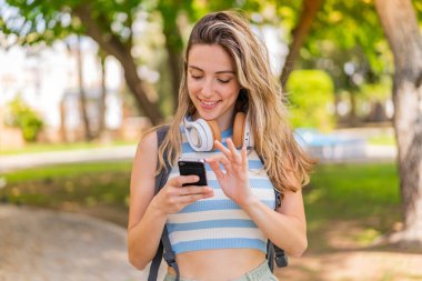 Dışarıda cep telefonu kullanan genç ve güzel bir kadın.