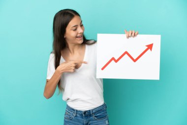 Genç Fransız kadın mavi arka planda izole edilmiş. Elinde büyüyen bir istatistik oku sembolü olan bir tabela var ve işaret ediyor.