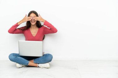 Genç Fransız kız dizüstü bilgisayarı ile yerde oturuyor. Gözlerini elleriyle kapatıyor.