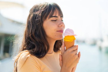 Açık havada kornet dondurmalı genç bir kadın.