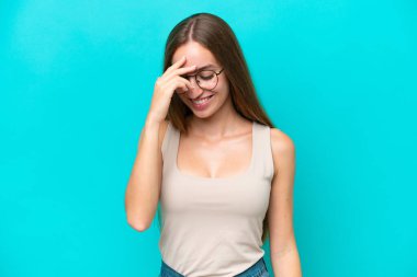 Mavi arka planda izole edilmiş genç beyaz kadın gülüyor.