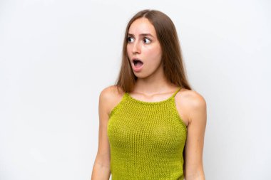 Beyaz arka planda izole edilmiş genç beyaz kadın yan tarafa bakarken sürpriz jest yapıyor.