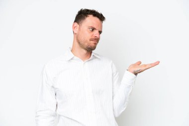 Beyaz arka planda izole edilmiş beyaz, beyaz, yakışıklı bir genç. Kopyalama alanını şüphe ile tutuyor.