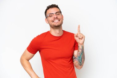 Beyaz arka planda izole edilmiş beyaz tenli yakışıklı bir adam en iyinin göstergesi olarak parmağını kaldırıyor.