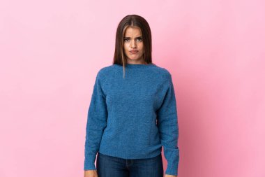 Genç Uruguaylı kadın üzgün bir ifadeyle pembe arka planda izole edilmiş.