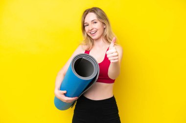 Genç beyaz kadın yoga derslerine gidiyor. Elinde sarı arka planda izole edilmiş bir minder var. Çünkü iyi bir şey oldu.