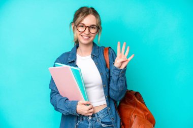 Mavi arka planda izole edilmiş genç bir bayan mutlu ve parmaklarıyla dört tane sayıyor.