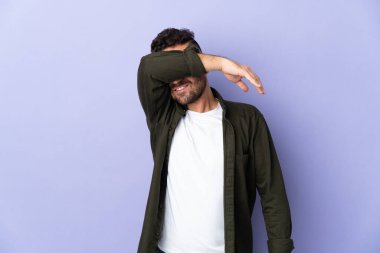 Mor arka planda izole edilmiş beyaz adam gözlerini elleriyle kapatıyor.