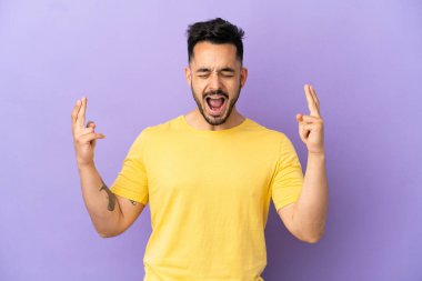 Genç beyaz adam mor arka planda izole edilmiş ve şans diliyor.