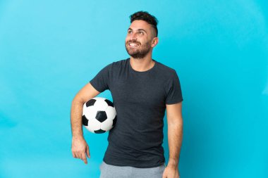 Futbolcu mavi arka planda izole edilmiş, yukarı bakarken bir fikir düşünüyor.