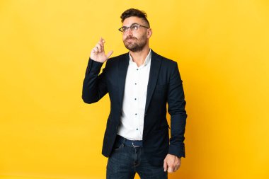 İzole edilmiş sarı arka planı olan işadamı şans diliyor ve en iyisini diliyor.