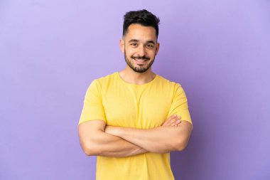 Mor arka planda izole genç beyaz adam kollarını ön pozisyonda çapraz tutuyor.