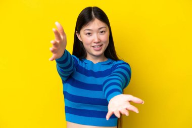 Sarı arka planda izole edilmiş genç bir Çinli kadın sunar ve davet eder.