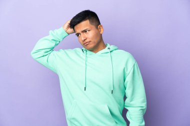 Genç Ekvadorlu adam mor arka planda izole edilmiş. Kafasını kaşırken şüpheleri var.
