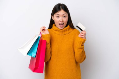 Beyaz arka planda izole edilmiş genç bir Çinli kadın elinde alışveriş torbalarıyla şaşırmış.