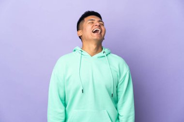 Genç Ekvadorlu adam, mor arka planda izole edilmiş gülüyor.