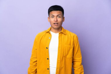 Genç Ekvadorlu, mor arka planda izole edilmiş, şaşırmış bir yüz ifadesi var.