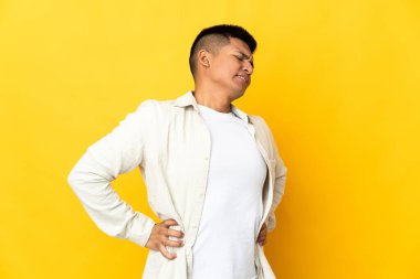 Genç Ekvadorlu adam sarı arka planda izole edilmiş, çabaladığı için sırt ağrısı çekiyor.