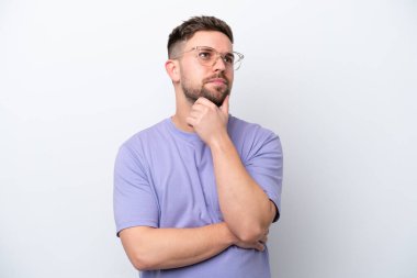 Beyaz arka planda soyutlanmış genç beyaz bir adamın şüpheleri var.