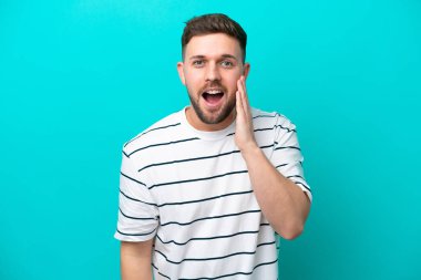 Mavi arka planda mahsur kalmış, şaşırmış ve şok olmuş genç bir beyaz adam.