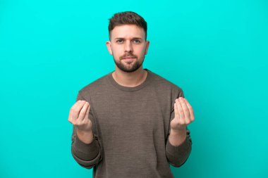 Kafkasyalı genç adam mavi arka planda izole edilmiş para hareketi yapıyor ama mahvolmuş.