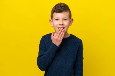 Sarı arka planda izole edilmiş küçük beyaz çocuk mutlu ve gülümsüyor.