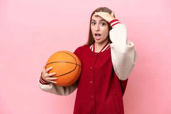 年轻的高加索篮球运动员女子 因粉红背景而被隔离在外 一边看一边做令人惊讶的动作 — 图库照片