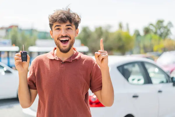 素晴らしいアイデアを指摘する屋外で車のキーを保持している若いアラビアのハンサムな男 — ストック写真