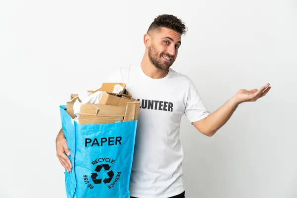 白い背景に隔離されたリサイクルするために紙でいっぱいのリサイクル袋を持っている白人男性が来るように招待するために手を伸ばします — ストック写真